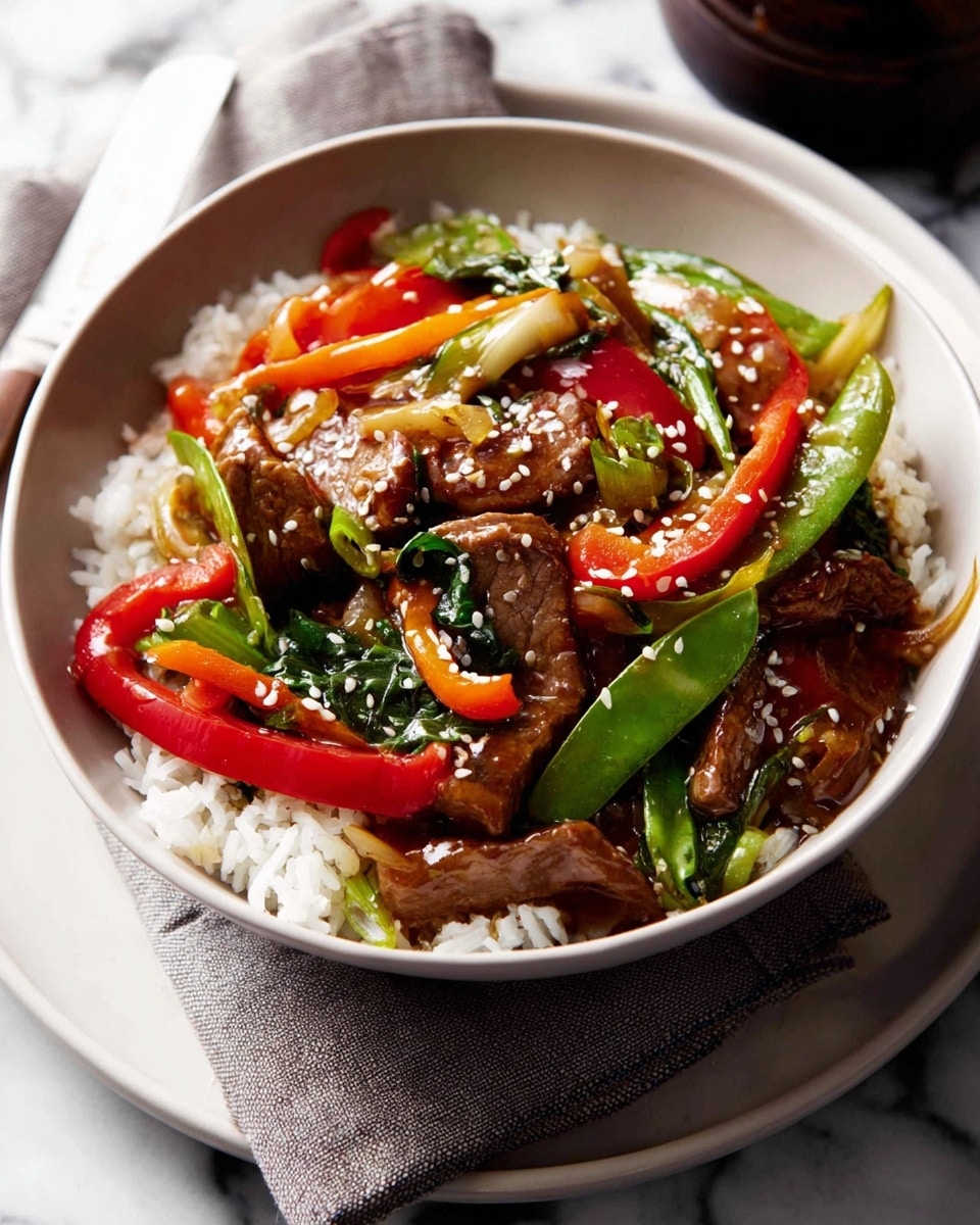 A white bowl filled with a base layer of white rice, topped with a colorful stir-fry layer featuring pieces of brown meat, bright red bell pepper strips, orange carrot slices, green leafy vegetables, and green snap peas, all coated in a shiny sauce with white sesame seeds sprinkled on top. The bowl is placed on a light gray cloth napkin over a white plate on a white marbled surface. Photo taken with an iphone --ar 4:5 --v 7