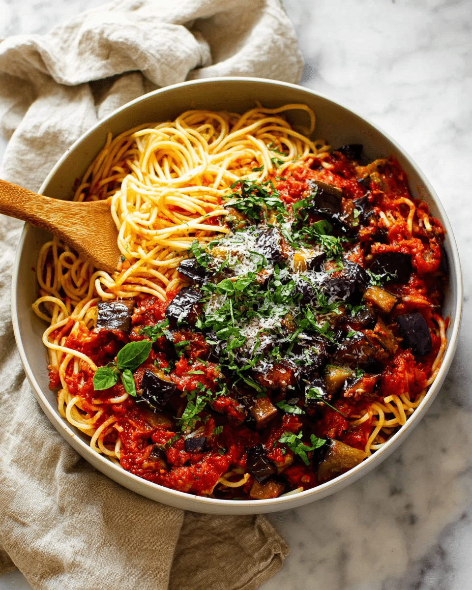 A large white bowl filled with three layers: at the bottom, thin spaghetti pasta twisted around a wooden spoon mixing it; in the middle, a rich red tomato sauce coats the noodles thickly; on top, chunky pieces of dark purple eggplant are scattered evenly; sprinkled over everything is a light dusting of grated cheese and fresh green chopped basil leaves. The bowl sits on a white marbled surface with a light beige cloth draped casually in the background. photo taken with an iphone --ar 4:5 --v 7