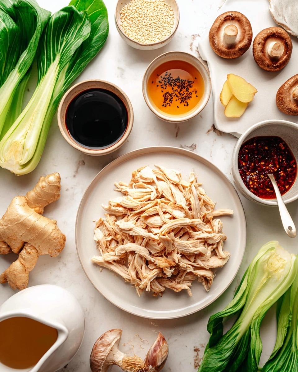 A white round plate at the center holds shredded cooked chicken with pale beige and light brown tones, showing a fibrous texture. Surrounding it are several small white bowls and plates with different ingredients: a bowl of dark soy sauce, a bowl with a light amber liquid drizzled with black spots resembling sesame oil, another bowl with deep red chili oil containing chunks and a white spoon resting inside, and a small bowl with pale beige sesame seeds. On a nearby white plate are slices of fresh ginger in yellow with a whole piece and several garlic cloves that are white and smooth. Fresh green onions in long bright green stalks and a bunch of bok choy with crisp green leaves and white stems lie on a white marbled surface. There are also fresh shiitake mushrooms with brown caps and white stems scattered around. A white ceramic pitcher containing a light brown liquid is partly visible at the edge. Photo taken with an iphone --ar 4:5 --v 7