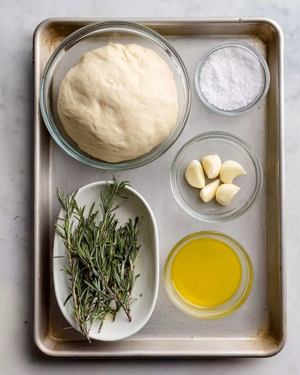 A metal baking tray holds five items on a white marbled surface. At the top left, a large glass bowl contains smooth, slightly puffy dough with a pale cream color and soft texture. To the right of the bowl is a small clear glass bowl filled with white coarse salt. Below these, at the bottom left, a white oval bowl contains several fresh rosemary sprigs with dark green, needle-like leaves. Centered below the glass bowl is a small clear glass bowl holding five peeled garlic cloves, off-white and smooth. At the bottom right is a small white bowl filled with bright yellow olive oil that has a shiny, liquid texture. The tray and all items are neatly arranged, showing simple cooking ingredients. Photo taken with an iphone --ar 4:5 --v 7