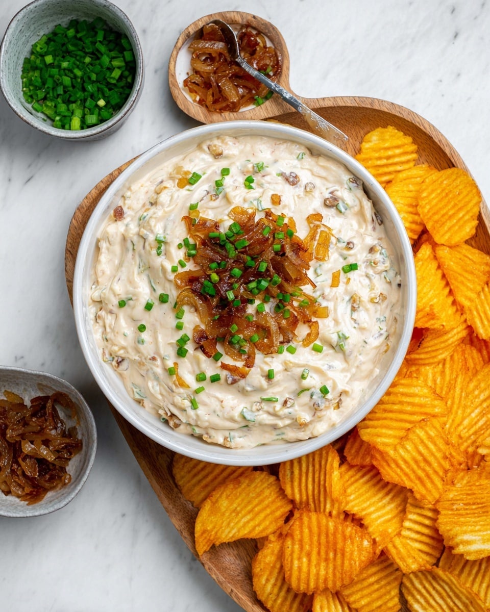 The image shows a white bowl filled with creamy dip that has a light beige color with small green and brown bits mixed in. On top of the dip, there are caramelized golden-brown onion pieces and bright green chopped chives placed in the center. Next to the bowl, there are bright orange ridged potato chips on a wooden tray. Around the tray, there are small side bowls filled with more caramelized onions and chopped chives. The whole setup is on a white marbled surface. photo taken with an iphone --ar 4:5 --v 7
