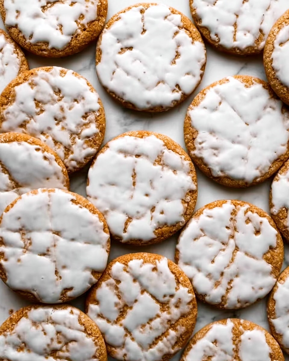 The image shows many round cookies topped with white icing, arranged closely on a white marbled surface. Each cookie has a golden-brown base with a slightly rough texture and is covered unevenly with smooth, glossy white icing that has thin, delicate cracks and patterns. The cookies are layered flat and fill the entire frame, making a visually rich pattern of light and warm brown mixed with white. photo taken with an iphone --ar 4:5 --v 7