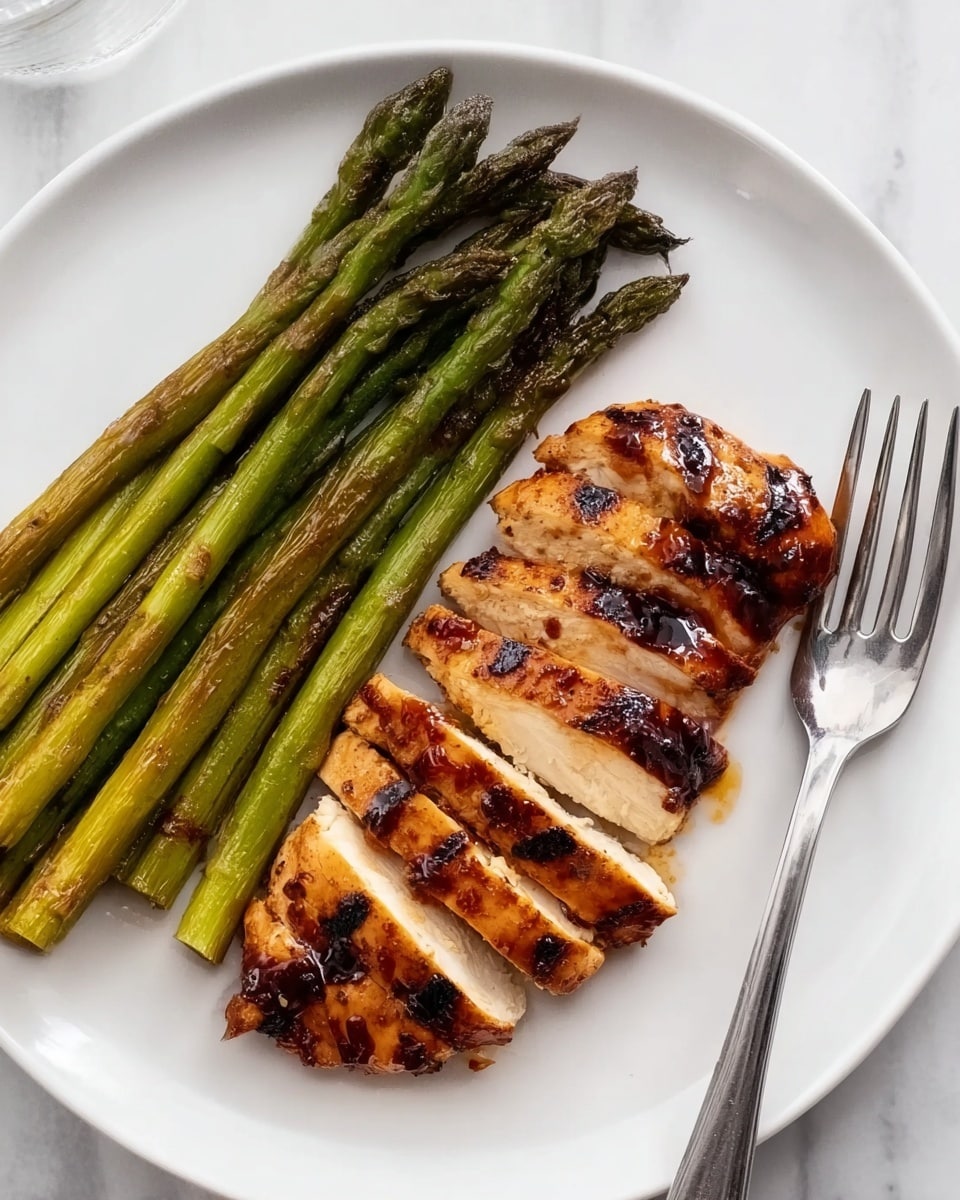 A white plate with grilled chicken sliced into five pieces arranged on the right side, showing a golden-brown outer layer with shiny glaze and white inside. On the left side, there are seven long, grilled asparagus stalks with a light char and a green color. A silver fork lies on the plate near the chicken. The plate sits on a white marbled surface. photo taken with an iphone --ar 4:5 --v 7