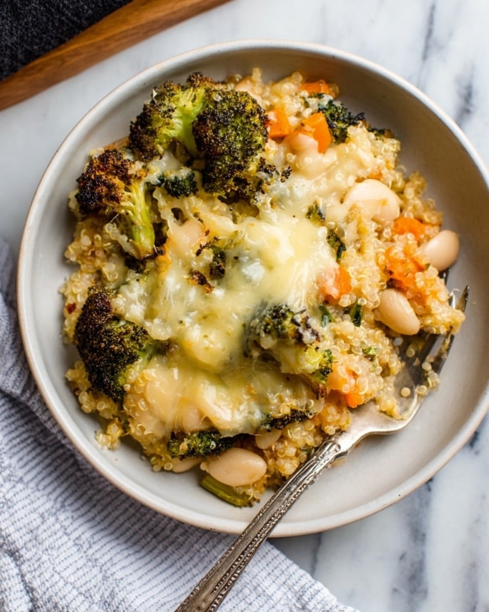 A white bowl filled with a layered dish showing roasted broccoli florets with browned edges on the top, melted light yellow cheese stretched over the broccoli and quinoa, white beans and small orange carrot pieces mixed in a middle beige quinoa layer which looks creamy and soft. A silver fork rests inside the bowl on the right side. The bowl sits on a white marbled surface with a white and blue striped cloth partially visible next to it. photo taken with an iphone --ar 4:5 --v 7