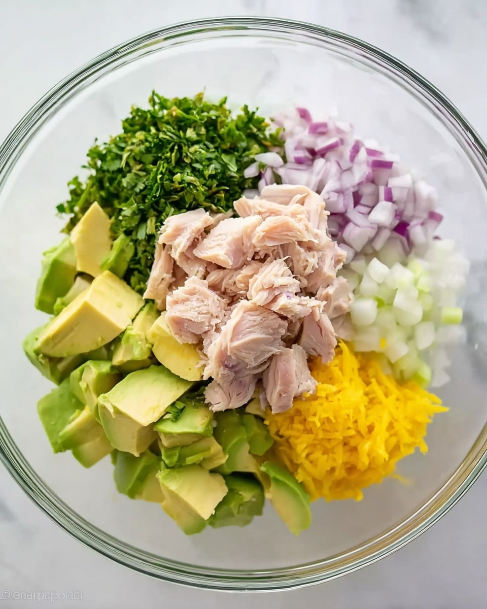 The image shows a clear glass bowl placed on a white marbled surface, containing six different layers of ingredients arranged side by side. There are chunks of light pink cooked turkey on the upper right, fresh chopped green herbs on the upper left, small diced red onions to the right middle, bright yellow lemon zest at the bottom right, small white diced celery pieces at the bottom middle, and larger pale green avocado cubes on the left. Each ingredient is separate and distinct with fresh, natural colors. photo taken with an iphone --ar 4:5 --v 7