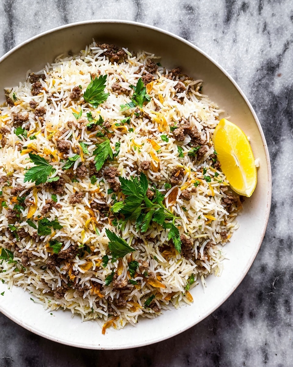 A large white bowl filled with a dish of white long-grain rice mixed with small pieces of browned ground meat, thin toasted pasta strands, and small yellow nuts scattered evenly throughout. On top near the edge, there is a garnish of fresh green parsley leaves and a bright yellow lemon wedge. The bowl sits on a white marbled surface. photo taken with an iphone --ar 4:5 --v 7
