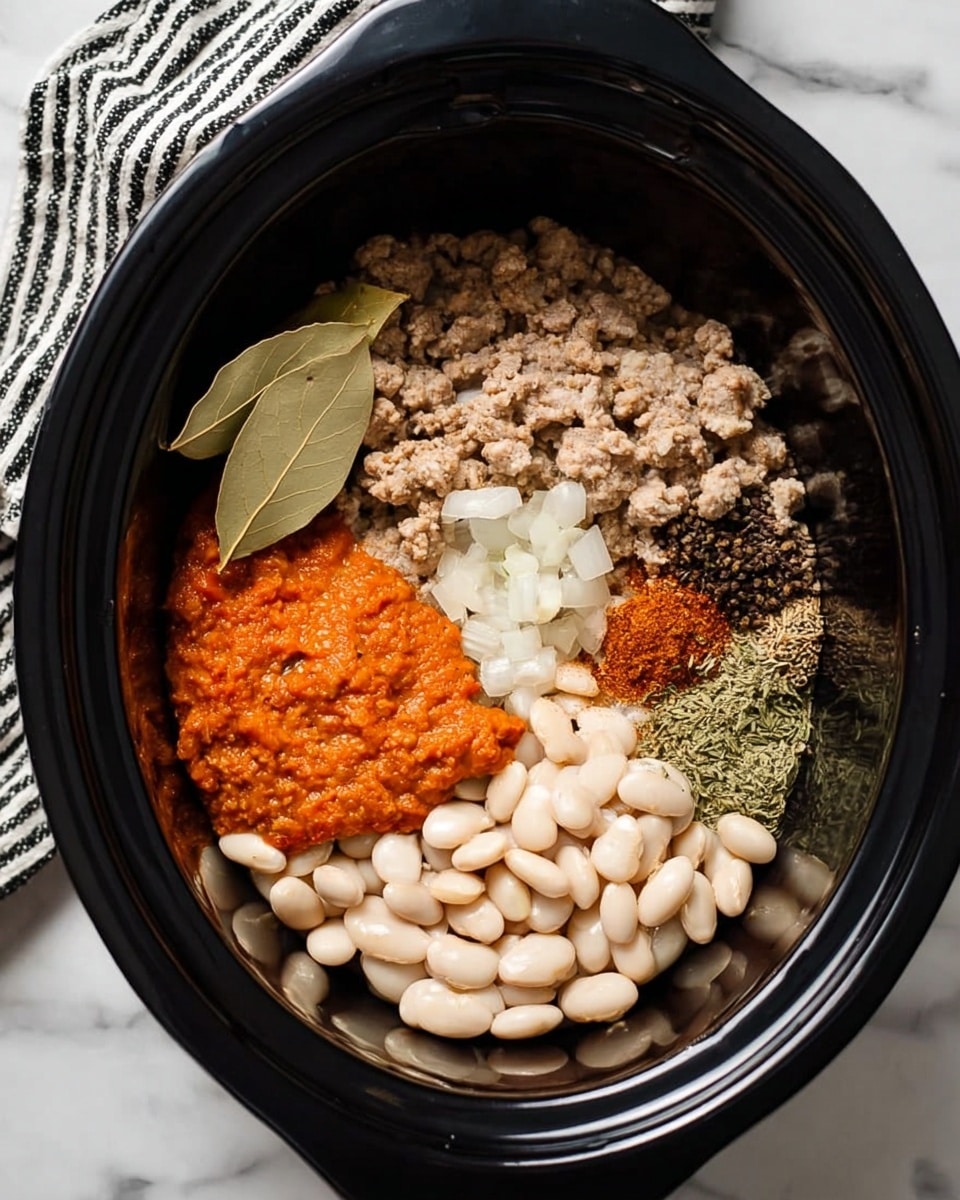 Inside a black slow cooker, there are six clear parts of ingredients placed separately but close to each other. Starting from the bottom right, there are smooth, shiny white beans, moving left to a thick, bright orange paste with a rough texture. Above the beans and paste, there is a section of pale beige cooked ground meat mixed lightly with small soft pieces of diced white onions. At the top right, there is a cluster of small, green chopped pieces, alongside a pile of dried mixed spices and herbs in brown, green, and black colors. On top of the meat, there are two large, dry bay leaves. The slow cooker is placed on a white marbled surface with a folded black and white striped cloth on the left side. Photo taken with an iphone --ar 4:5 --v 7