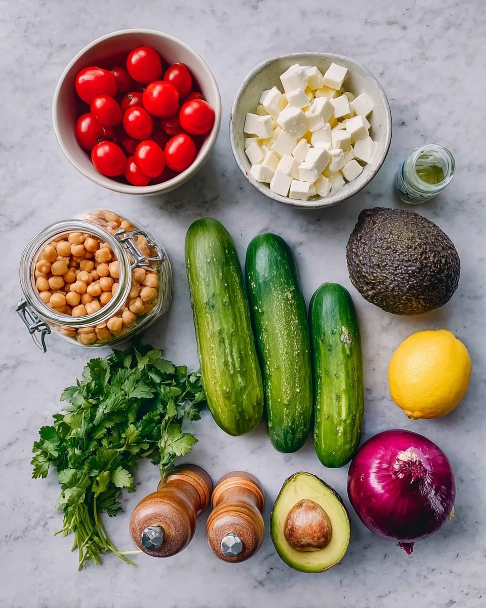 The image shows a collection of fresh ingredients for a salad arranged on a white marbled surface. There are two white bowls: one filled with small bright red grape tomatoes and the other with white cubed cheese. Next to the bowls are three whole green cucumbers lying side by side, a bunch of green cilantro leaves, a whole purple onion, a single garlic clove, an avocado with rough dark green skin, and a bright yellow lemon. There is also an open can filled with light brown chickpeas, a small clear glass bottle with a cork top, and two wooden pepper and salt shakers standing upright near the center. The scene is neatly organized and colorful, with natural light highlighting the fresh textures. Photo taken with an iphone --ar 4:5 --v 7