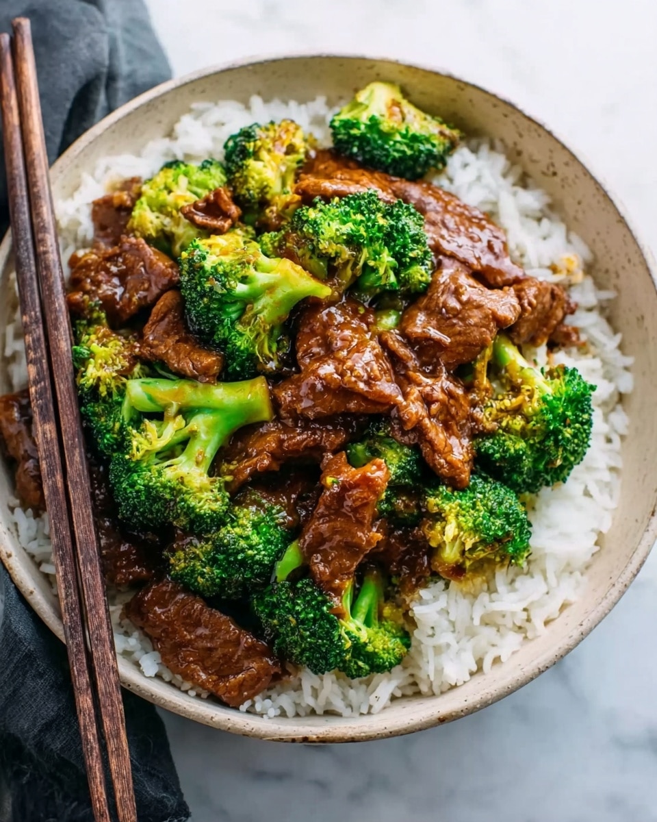 A white bowl filled with a base layer of fluffy white rice. On top, there are chunks of beef covered in thick brown sauce, mixed with bright green broccoli florets. The beef pieces look tender and glossy, while the broccoli adds a fresh and vibrant texture. A pair of dark wooden chopsticks rest on the edge of the bowl, all placed on a white marbled surface. Photo taken with an iphone --ar 4:5 --v 7