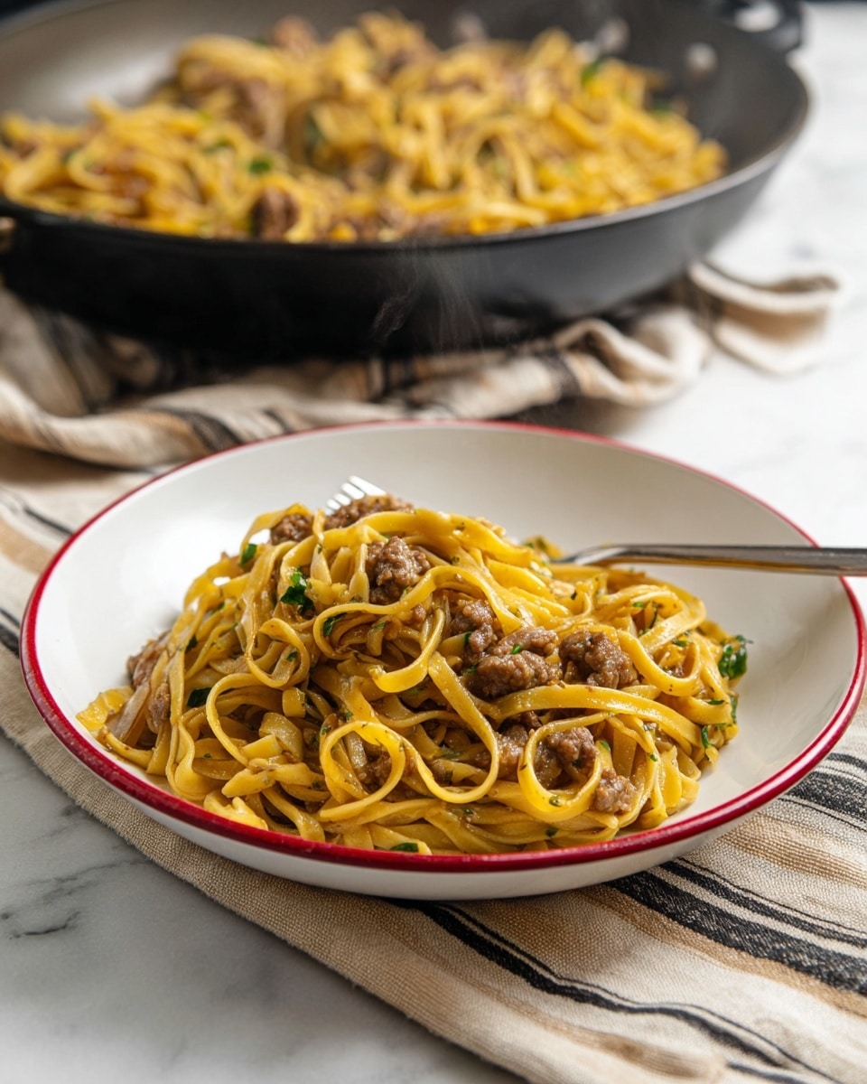 A white shallow bowl with a red rim holds a serving of thick yellow noodles mixed with small browned meat pieces and bits of green herbs, all coated in a light sauce with a slightly glossy texture. The noodles are layered loosely and piled in the center of the bowl, with some strands slightly twisted and overlapping. Behind it, a black pan filled with a similar noodle and meat mix sits on top of a cloth with beige and dark stripes, all set on a white marbled surface. A silver fork is placed inside the bowl on the right side. Steam rises gently from the noodles. Photo taken with an iphone --ar 4:5 --v 7