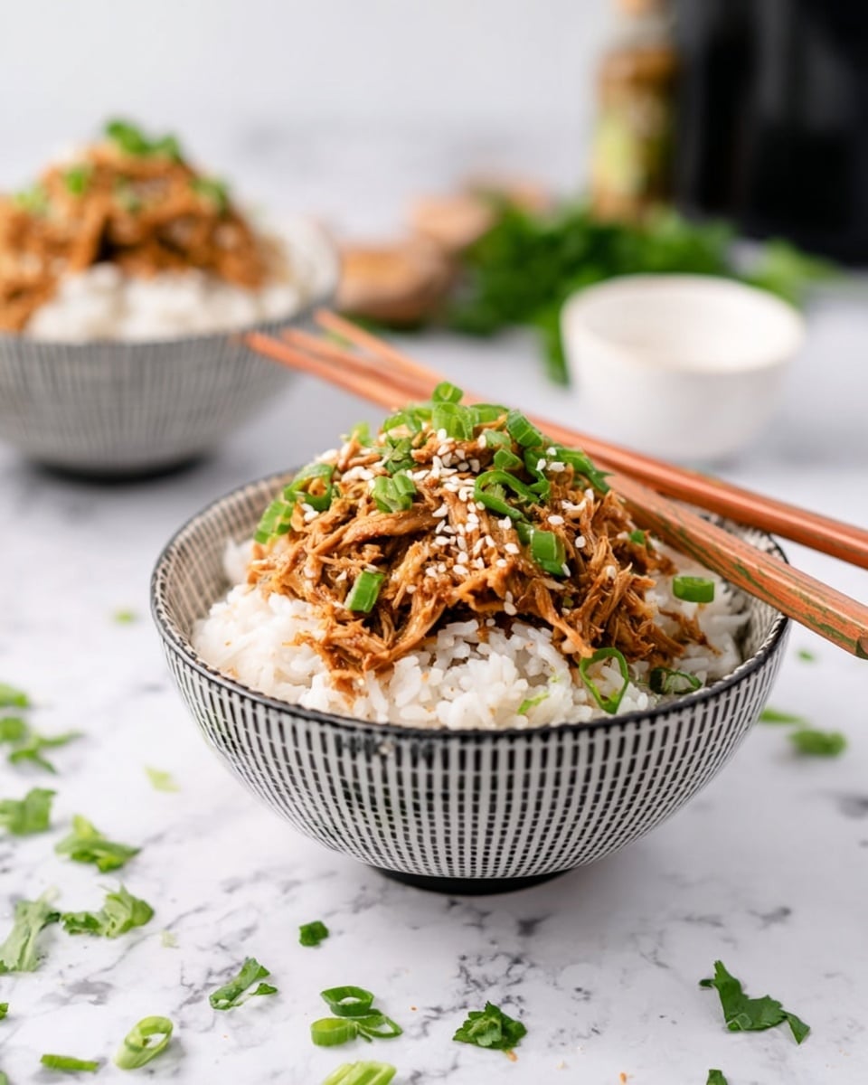 A bowl with a white and black pattern holds a layer of white rice, topped with a layer of shredded light brown cooked meat mixed with sauce. The meat is sprinkled with green sliced herbs and white sesame seeds. A pair of wooden chopsticks rest on the bowl's edge. The bowl sits on a white marbled surface, with scattered green herb pieces nearby. In the background, another similar bowl is blurred, also filled with rice and meat, with a blurred bottle and a small white bowl to the side. photo taken with an iphone --ar 4:5 --v 7